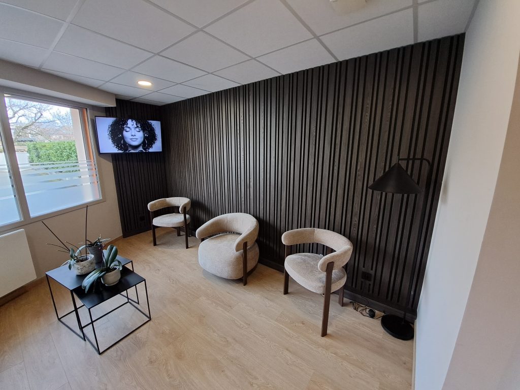 Salle d'attente moderne du cabinet Griotier avec fauteuils beiges et mur en lattes noires